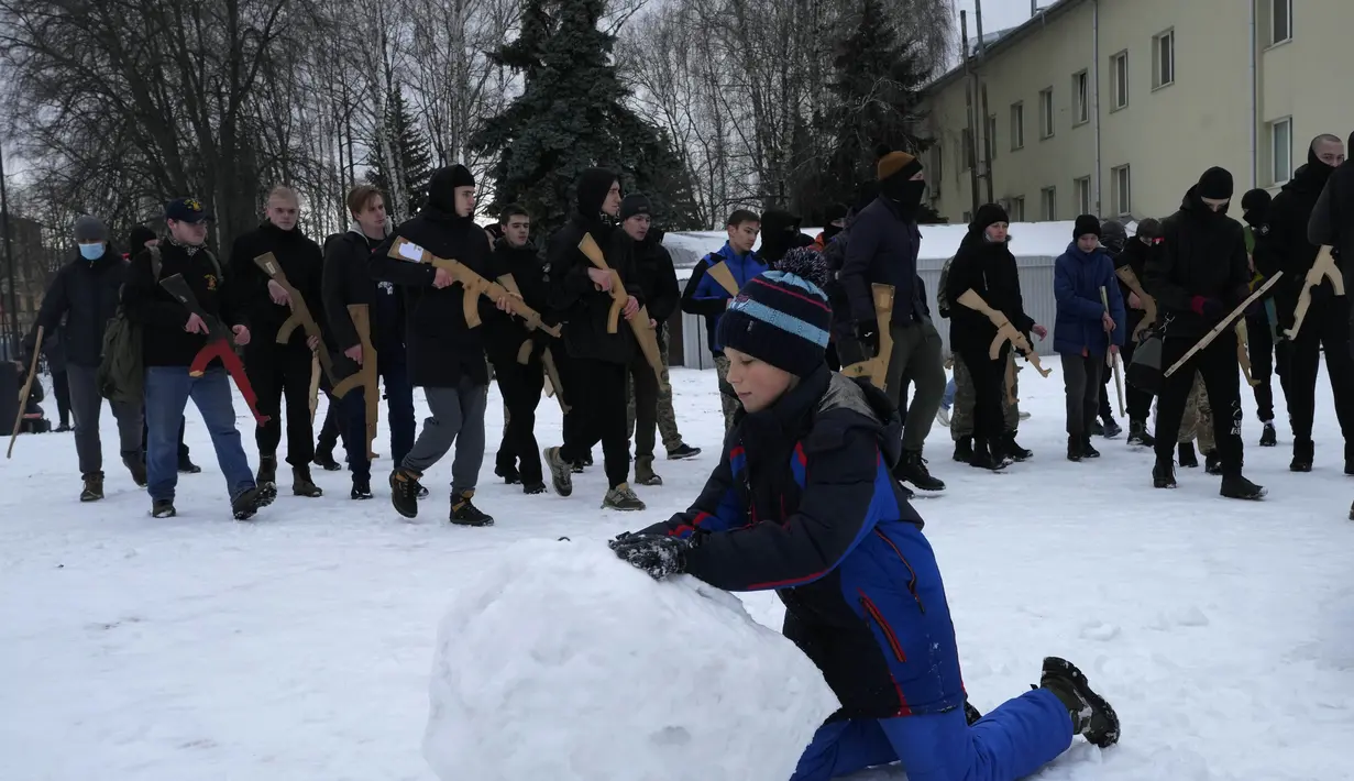 Seorang anak laki-laki membuat bola salju sementara penduduk setempat mengambil bagian dalam pelatihan pertahanan militer di Kyiv, Ukraina (30/1/2022). Menteri Luar Negeri Sergey Lavrov juga menantang klaim NATO sebagai struktur pertahanan murni. (AP Photo/Efrem Lukatsky)