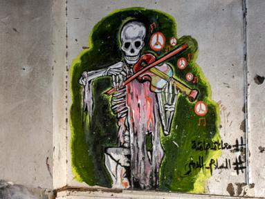 Foto yang diambil pada 10 Mei 2023 ini menunjukkan salah satu mural yang digambar oleh seniman jalanan Yaman, Alaa Rubil yang menggambarkan kerangka yang sedang memainkan alat musik biola dan dilukis di dinding di kota pelabuhan selatan Aden. (Saleh Al-OBEIDI / AFP)
