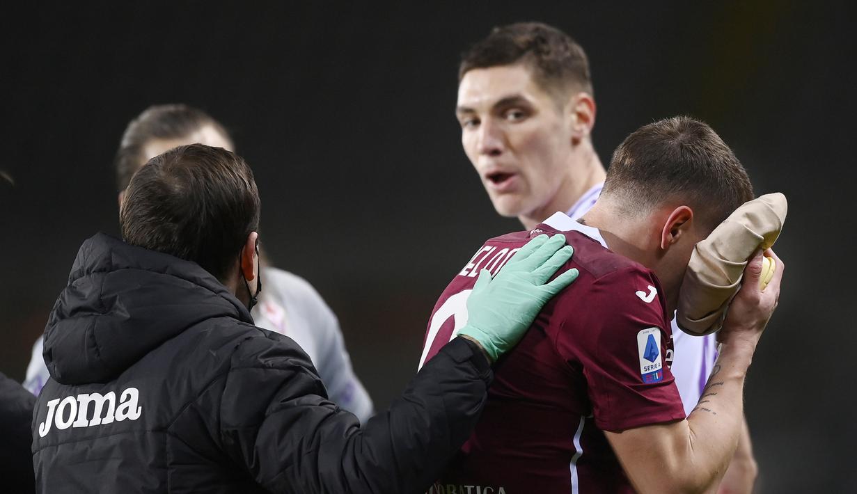Striker Torino, Andrea Belotti (kanan) mendapat perawatan usai ditanduk bek Fiorentina, Nikola Milenkovic dalam laga lanjutan Liga Italia 2020/21 pekan ke-20 melawan Fiorentina di Olympico Grande Stadium, Jumat (29/1/2021). Torino bermain imbang 1-1 dengan Fiorentina. (LaPresse via AP/Fabio Ferrari)