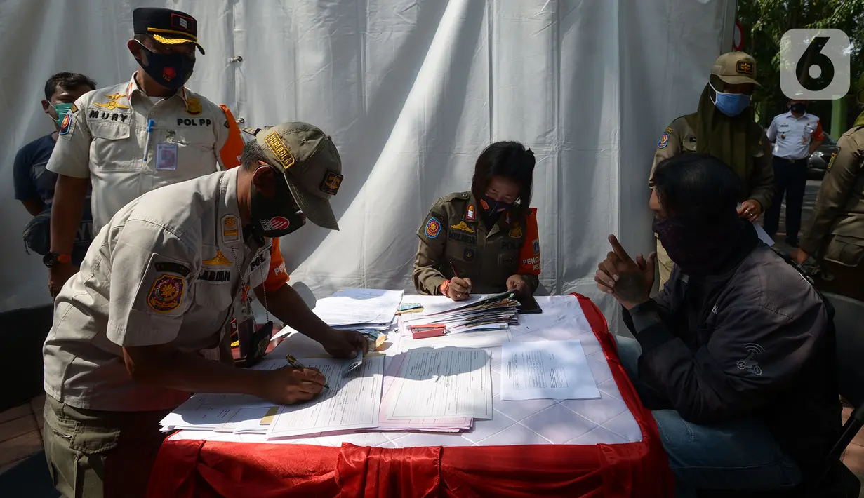 Aparat gabungan mendata pelanggar yang terjaring razia saat Operasi Yustisi di Kawasan Danau Sunter, Jakarta, Rabu (16/9/2020). Warga yang tidak memakai masker langsung disidang tindak pidana ringan (tipiring) di tempat dengan membayar denda Rp 55.000 maupun sanksi sosial. (merdeka.com/Imam Buhori)