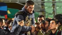Juara kelas ringan UFC, Khabib Nurmagomedov membawa sabuk juaranya saat disambut oleh para penggemar setibanya di Makhachkala, Rusia, Senin (8/10). Nama Khabib menjadi terkenal setelah dirinya berhasil mengalahkan Conor McGregor. (AFP/Vasily MAXIMOV)