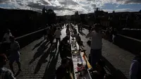 Warga menggelar makan malam di atas meja sepanjang 500 meter di jembatan bersejarah Charles Bridge di Praha, Republik Ceko, Selasa (30/6/2020). Kegiatan itu merupakan perpisahan simbolis yang digelar untuk menandai akhir dari masa krisis virus corona Covid-19 di negara tersebut (AP/Petr David Josek)