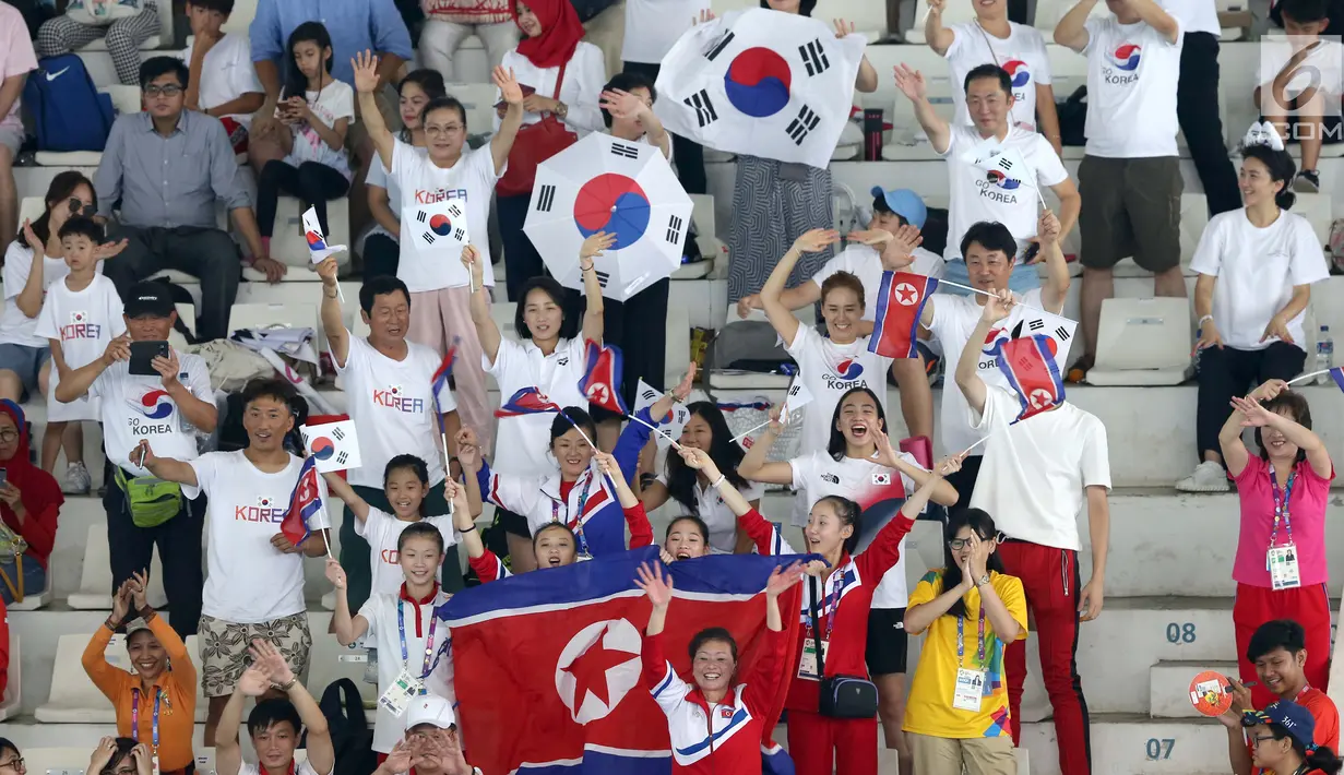 Pendukung Korea Utara dan Korea Selatan saat menyaksikan tim renang artistik Korea Utara  pada babak final nomor free routine Asian Games 2018 di Aquatic Center, Gelora Bung Karno, Jakarta, Rabu (29/8). (Liputan6.com/Fery Pradolo)