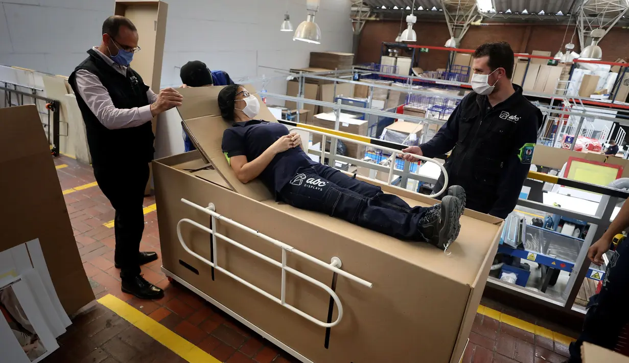 Rodolfo Gomez dan karyawannya mendemonstrasikan desain kardus mereka dapat berfungsi sebagai tempat tidur rumah sakit dan peti mati untuk pasien COVID-19 di Bogota, Kolombia, Jumat (8/5/2020). Perusahaan ini menanggapi kekurangan tempat tidur dan peti mati selama pandemi.  (AP/Fernando Vergara)