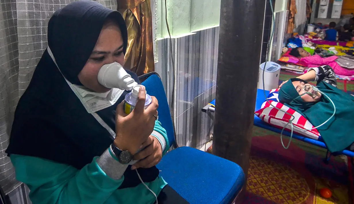 Warga yang terpapar kabut asap karhutla menghirup oksigen ketika berada di Rumah Singgah Korban Asap di Pekanbaru, Riau, Jumat (20/9/2019). Data Kemenkes sebanyak 15.346 warga di Provinsi Riau menderita ISPA akibat kabut asap karhutla dalam kurun waktu September 2019. (Wahyudi/AFP)