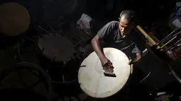Pembuat rebana tradisional, Fajar Siddiq memberikan sentuhan akhir pada rebana di rumahnya di Lambaro, Provinsi Aceh, Senin (22/2/2021). Usaha produksi berbagai jenis alat musik tradisional Aceh berupa rapai, serune kale dan seruling mulai langka. (CHAIDEER MAHYUDDIN / AFP) 