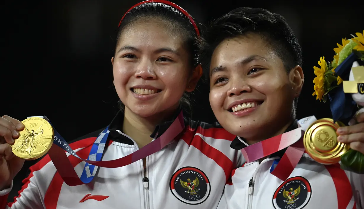 Ganda putri Indonesia Apriyani Rahayu dan Greysia Polii berpose dengan medali emas cabang badminton ganda putri Olimpiade Tokyo 2020 di Musashino Forest Sport, Senin (2/8/2021). Greysia / Apriyani merebut emas usai menang atas pasangan China Cheng Qingchen/Jia Yi Fan. (Alexander NEMENOV/AFP)
