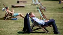 Seorang warga Inggris berjemur di atas kursi sambil menikmati sinar matahari di Green Park, London, Senin (25/6). Pada Juli 2018, suhu di ibu kota London tercatat 29.1 derajat Celcius dan diprediksi akan mencapai 30 derajat Celcius. (AFP/Tolga Akmen)
