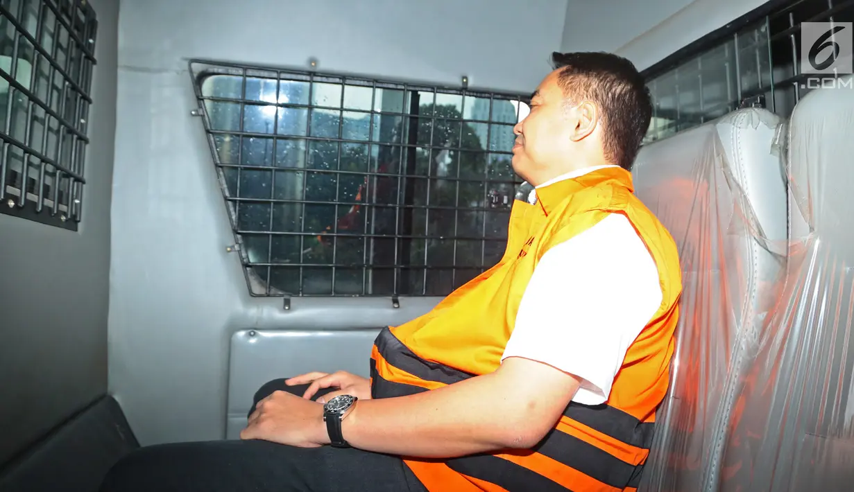 Tersangka anggota DPR Fayakhun Andriadi mengenakan rompi oranye berada di mobil tahanan usai menjalani pemeriksaan di Gedung KPK, Jakarta, Rabu (28/3). (Liputan6.com/Herman Zakharia)