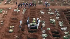 Petugas dengan pakaian pelindung menurunkan peti mati seseorang yang meninggal karena komplikasi COVID-19 ke dalam kuburan di pemakaman Vila Formosa di Sao Paulo, Brasil, Rabu (7/4/2021). Sao Paulo pada Rabu mulai menggali 600 kuburan tambahan setiap hari di pemakaman kotanya (AP Photo/Andre Penner)