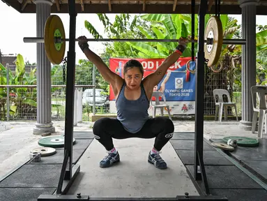Atlet angkat besi Olimpiade dari Filipina, Hidilyn Diaz mengangkat beban ketika berlatih di Jasin di kota Malaka, Malaysia pada 21 Mei 2021. Diaz (30) yang memenangkan perak di Rio 2016 lalu telah tertahan di Malaysia sejak Februari 2020 karena pandemi virus corona. (Mohd RASFAN/AFP)