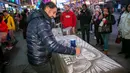 Amir Hussain yang berkunjung dari Denmark menggunakan garam meja untuk memberikan penghormatan kepada mendiang legenda sepak bola Pele di Times Square, New York, Amerika Serikat, 29 Desember 2022. (AP Photo/Ted Shaffrey)