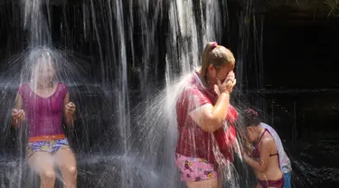 Orang-orang menyejukkan diri dari cuaca yang sangat terik di sungai saat gelombang panas di Paraguari, Paraguay, Minggu (16/1/2022). Suhu Paraguay secara umum mencapai 41 derajat celsius. (AP Photo/Jorge Saenz)