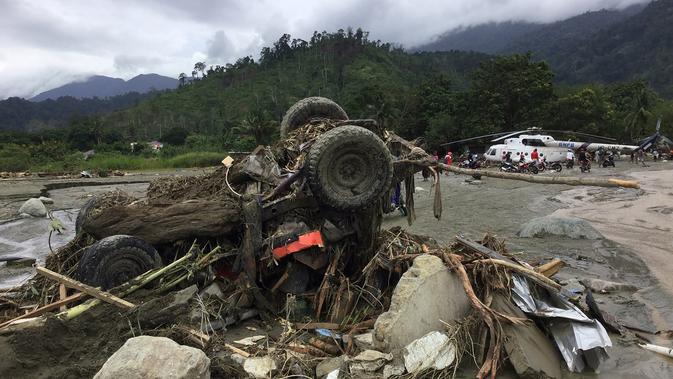 Sebuah kendaraan yang hanyut dengan puing-puing tersapu banjir bandang di Kabupaten Sentani, Jayapura, (17/3). Banjir bandang Sentani menewaskan 70 orang dan puluhan luka-luka. (AFP/Netty Dharma Somba)