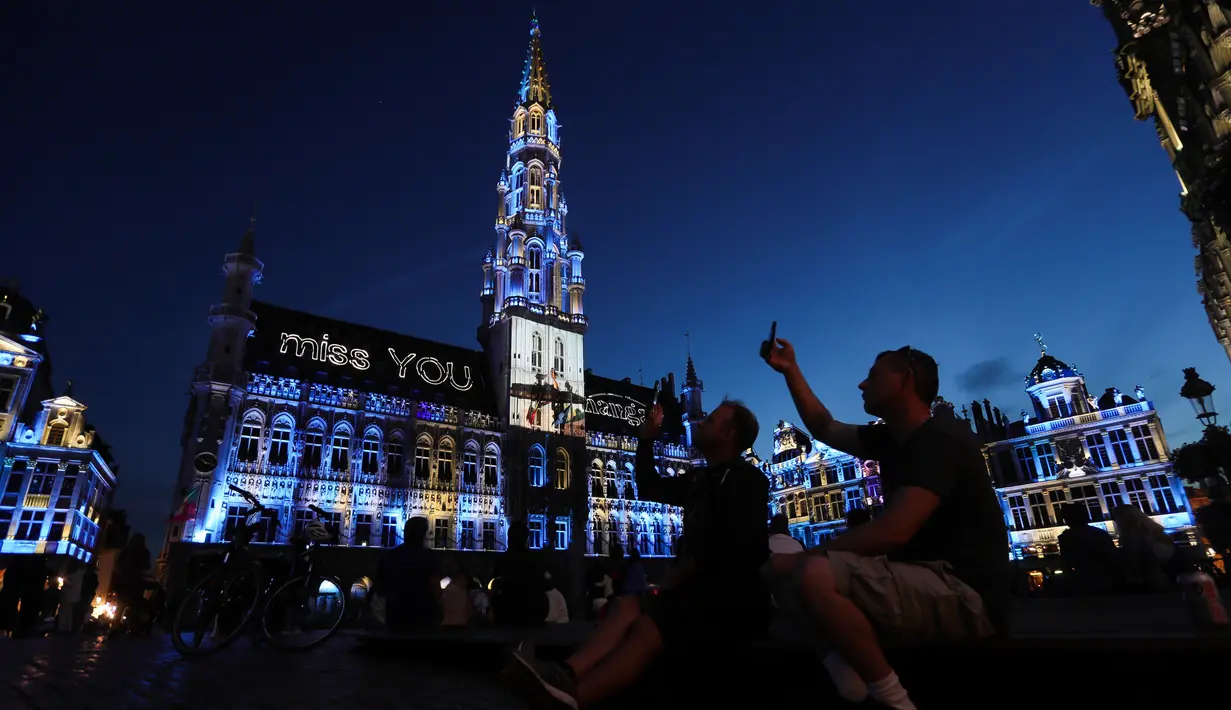 Warga menonton pertunjukan suara dan cahaya di Grand Place, Brussel, Belgia, Rabu (29/7/2020). Pertunjukan suara dan cahaya ini untuk menyoroti acara-acara yang batal digelar di Belgia pada musim panas tahun ini akibat pandemi COVID-19. (Xinhua/Zheng Huansong)