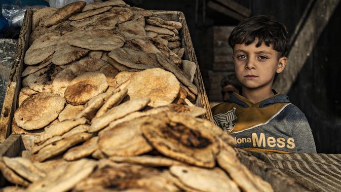 Seorang anak laki-laki menjual roti di kota Raqqa, bekas ibu kota ISIS, di Suriah utara pada 20 Desember 2020. Raqqa menjadi saksi terusirnya anggota kelompok ekstremis oleh Pasukan Demokratik Suriah pada Oktober 2017 lalu. (Photo by Delil SOULEIMAN / AFP)