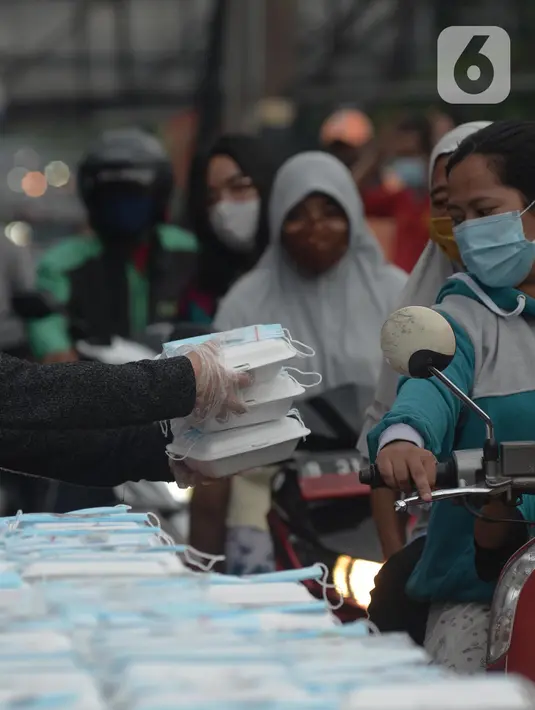 Warga menerima pembagian nasi bungkus gratis di Posko Perjuangan Rakyat (POSPERA), Jakarta, Rabu (10/3/2021). Pembagian 500 nasi bungkus beserta masker dan vitamin secara gratis setiap harinya dalam bentuk meringankan beban warga di tengah pandemi Covid-19. (merdeka.com/Imam Buhori)