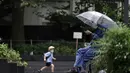 Seorang pria memakai masker melihat ponselnya di sebuah taman di Tokyo, Rabu, (23/9/2020). Badai tropis di Samudra Pasifik perlahan mendekati wilayah Tokyo pada hari Rabu, dan para pejabat mendesak penduduk berhati-hati dari perkiraan hujan lebat dan hembusan angin. (AP Photo/Eugene Hoshiko)