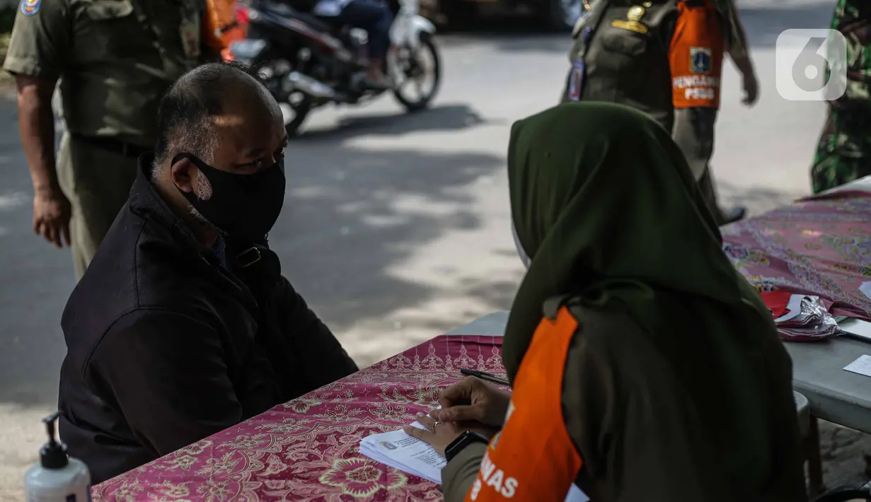 Petugas mendata seorang pelanggar tanpa masker saat razia masker di kawasan Karang Tengah Lebak Bulus, Jakarta, Selasa (24/11/2020). Pemerintah Provinsi (Pemprov) DKI Jakarta mencatat, total denda pelanggaran protokol kesehatan mencapai Rp 4,9 miliar. (Liputan6.com/Faizal Fanani)