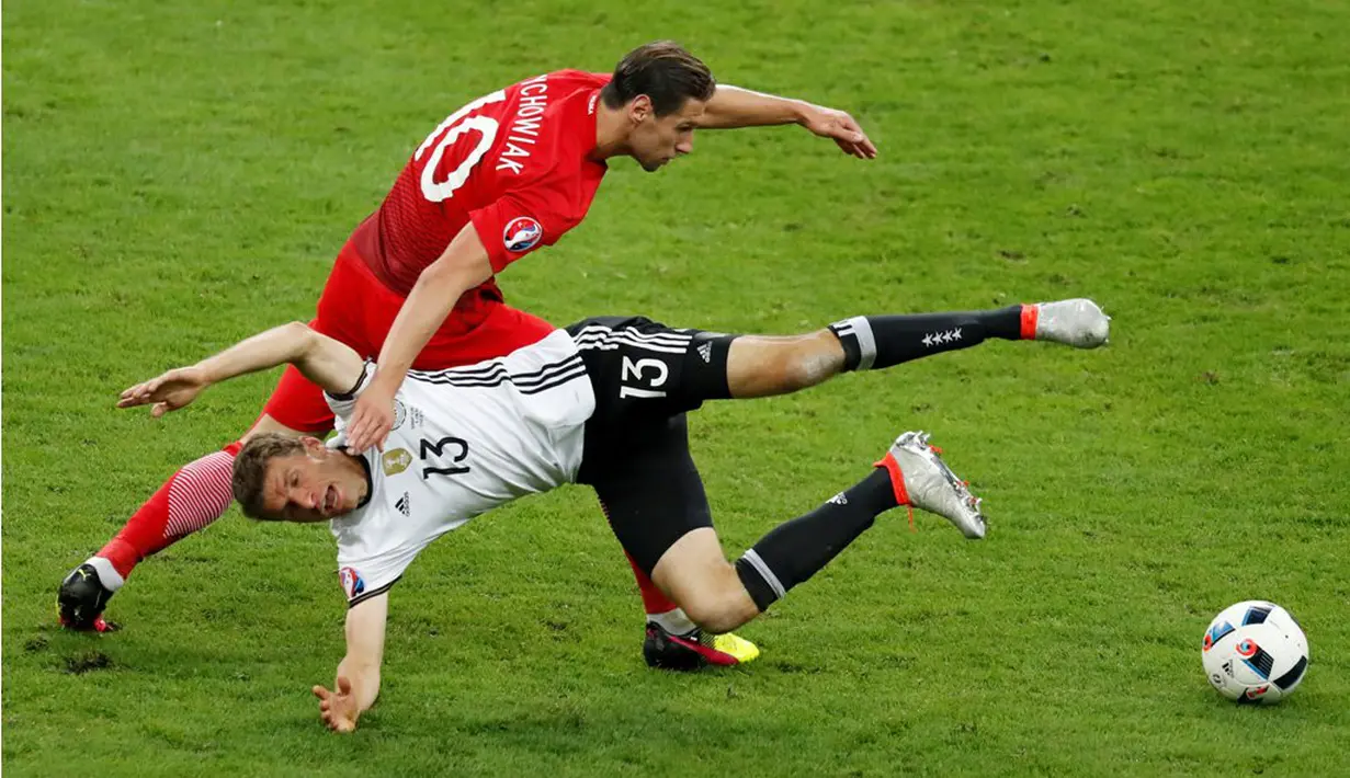 Pemain Jerman, Thomas Muller, terjatuh saat berebut bola dengan pemain Polandia, Grzegorz Krychowiak, pada laga kedua Grup C Piala Eropa 2016 di Stade de France, Jumat (17/6/2016) dini hari WIB. (Reuters/Charles Platiau)