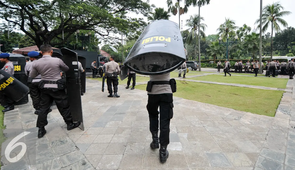 Petugas polisi membawa tameng untuk bersiap menjaga aksi di halaman Balai Kota, Jakarta, Jumat (4/11). Unjuk rasa besar-besaran ini diperkirakan akan diramaikan oleh 100 ribu orang . (Liputan6.com/Yoppy Renato)