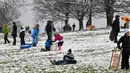 Orang-orang bermain dengan salju di Primrose Hill saat London mengalami hujan salju yang jarang terjadi pada Minggu (24/1/2021). Hujan salju langka di ibu kota Inggris itu membawa kegembiraan di tengah penguncian atau penutupan wilayah (lockdown) secara nasional. (JUSTIN TALLIS/AFP)