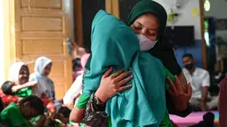 Seorang anak penderita cerebral palsy menerima pelukan dari ibunya saat berkumpul bersama keluarga untuk memperingati Hari Cerebral Palsy Sedunia di pusat fisioterapi Yayasan Sahabat Difabel di Banda Aceh (6/10/2021). (AFP/Chaideer Mahyuddin)