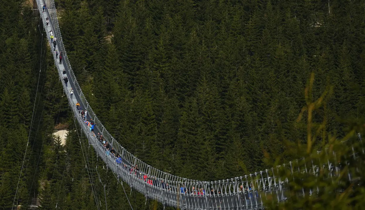 Pengunjung melintasi jembatan gantung untuk pejalan kaki yang merupakan konstruksi terpanjang di dunia setelah pembukaan resminya di sebuah resor pegunungan di Dolni Morava, Republik Ceko, Jumat (13/5/2022). Jembatan sepanjang 721 meter (2.365 kaki) dibangun pada ketinggian lebih dari 1.100 meter di atas permukaan laut. (AP Photo/Petr David Josek)