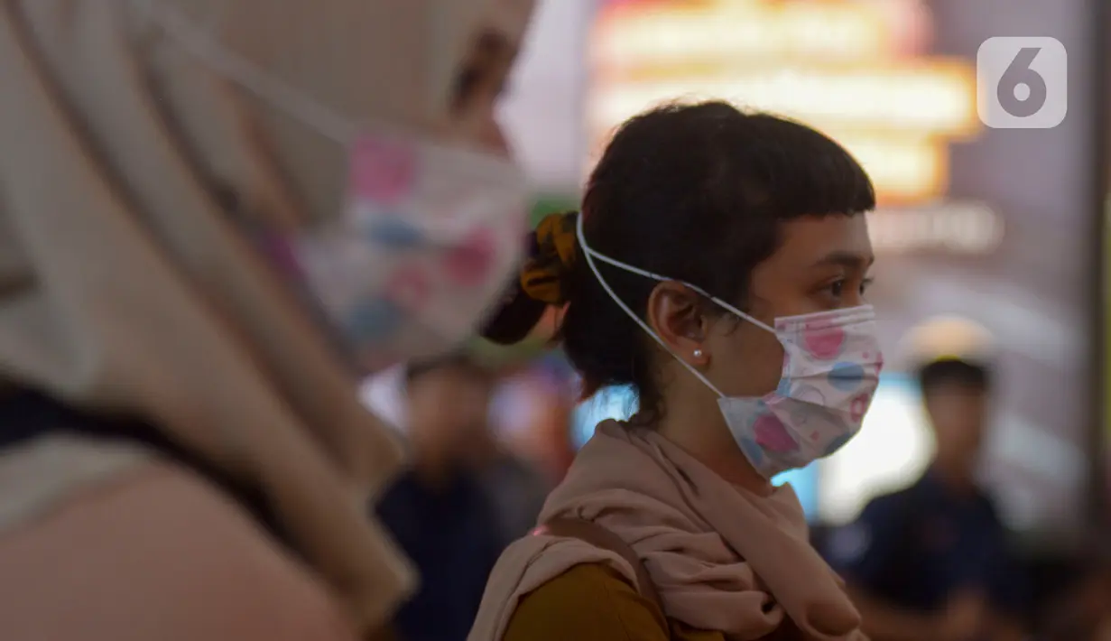 Calon penumpang kereta api mengenakan masker saat berada di Stasiun Gambir, Jakarta Pusat, Jumat (31/01). Dalam rangka pencegahan Virus Corona, PT Kereta Api Indonesia (persero) melakukan sosialisasi kepada penumpang dengan membagi-bagikan masker di stasiun Gambir. (merdeka.com/Imam Buhori)