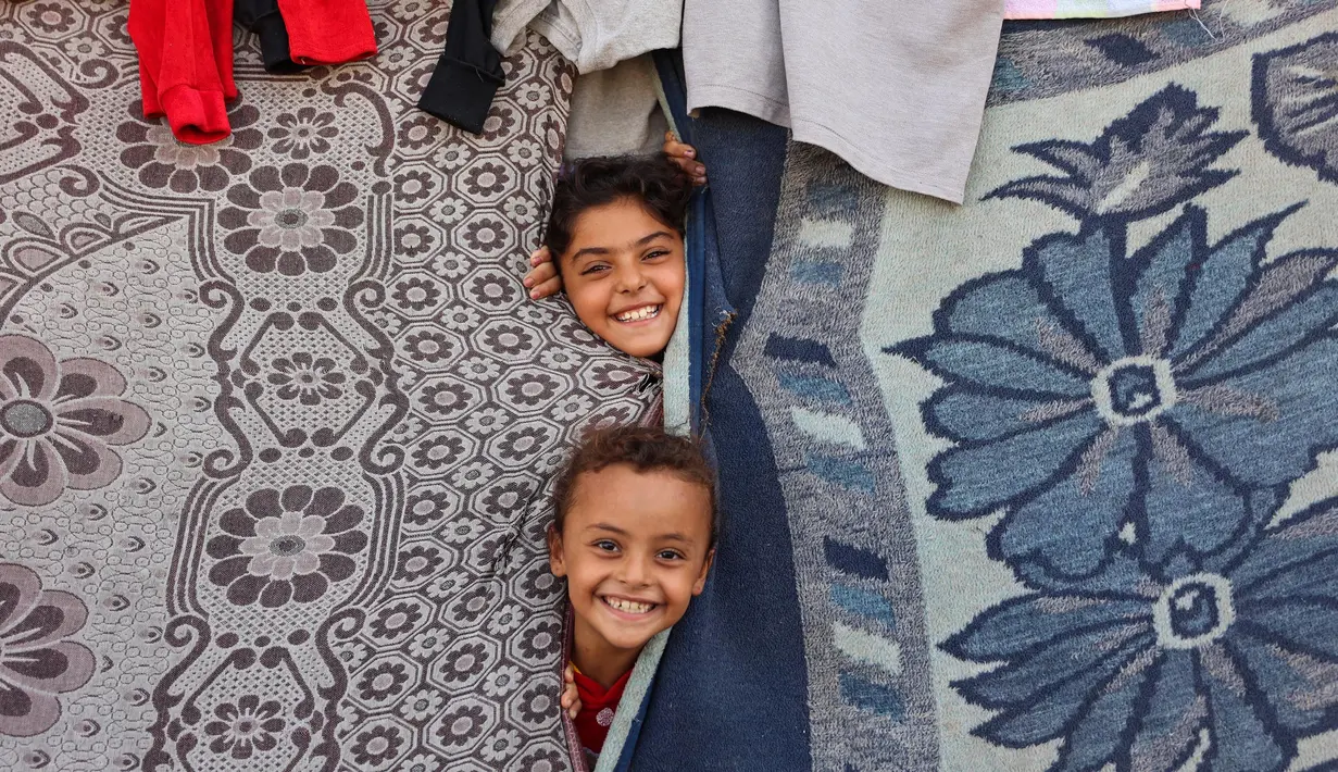 Anak-anak bermain di sebuah tenda darurat untuk warga Palestina yang mengungsi dari Gaza utara, di stadion Yarmouk yang rusak di Kota Gaza pada 14 Oktober 2024. (Omar AL-QATTAA/AFP)