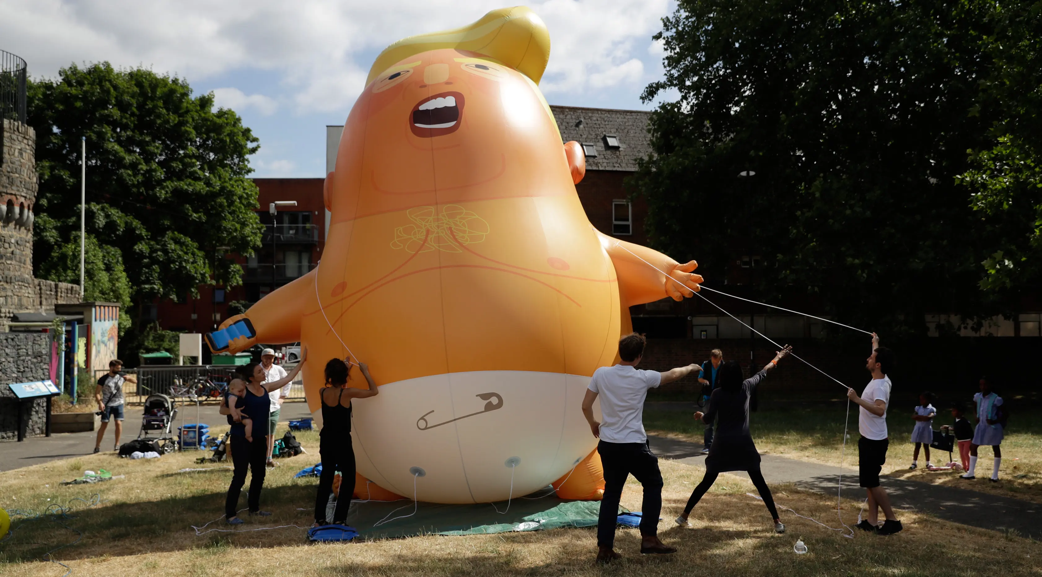 Aktivis mengembangkan balon berbentuk bayi Presiden AS Donald Trump di Bingfield Park, London, 10 Juli 2018. Balon bayi atau disebut Trump Baby itu akan diterbangkan ketika Trump melakukan lawatan perdana ke Inggris pada Kamis (12/7).  (AP /Matt Dunham)