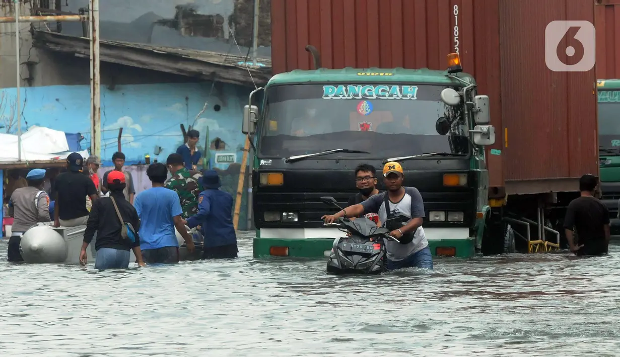 Pengendara sepeda motor mendorong kendaraannya melewati banjir rob di kawasan Pelabuhan Sunda Kelapa, Jakarta, Selasa (7/12/2021). Banjir rob setinggi satu meter memutus Jalan Kerapu yang menghubungkan Ancol-Pluit. (merdeka.com/Arie Basuki)