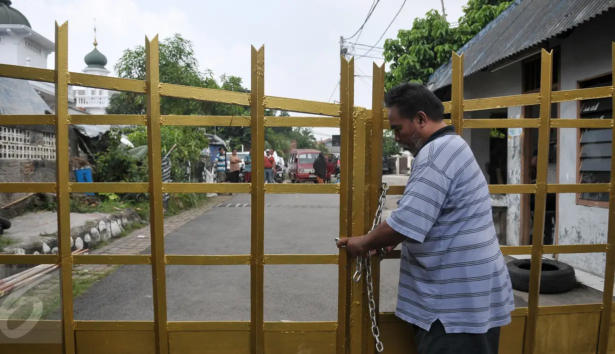 Seorang warga perumahan Eks Yon Angkub, Cililitan Besar, Jakarta, menggembok gerbang perumahan sebagai bentuk penolakan eksekusi rumah, Rabu (14/9).  Eksekusi rumah di kawasan itu mendapat penolakan warga. (Liputan6.com/Yoppy Renato)