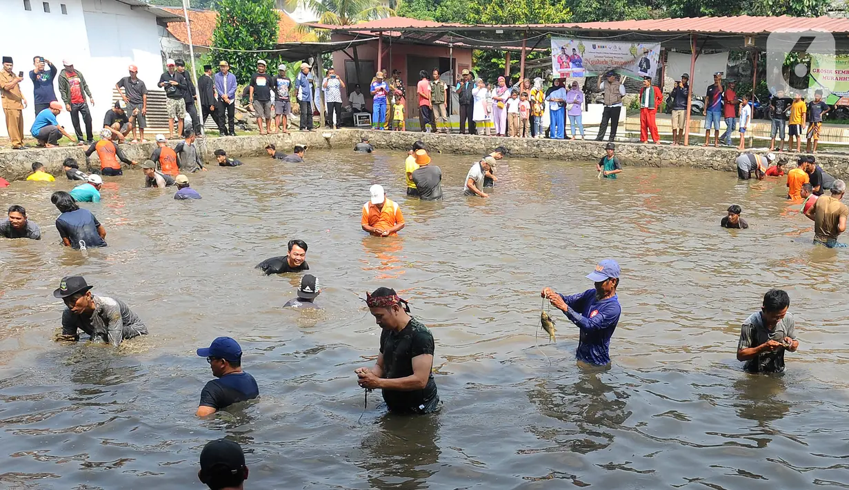 Warga menangkap ikan dengan tangan kosong saat acara Ngubek Empang di kawasan Bojongsari, Depok, Jawa Barat, Senin (15/5/2023). Kegiatan ini merupakan rangkaian Lebaran Depok Jilid 5. (merdeka.com/Arie Basuki)