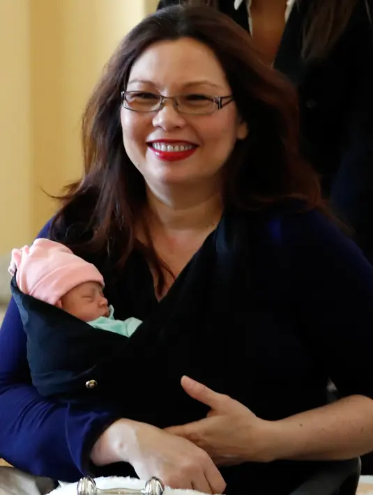 Senator Illinois, Tammy Duckworth membawa bayinya meninggalkan ruang kongres Gedung Capitol Hill, Washington DC, Kamis (19/4). Dengan suara bulat, pada Rabu (18/4), senat AS mengizinkan orang tua membawa bayi mereka ke ruangan kerja. (AP/Alex Brandon)