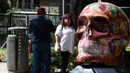 Seorang perempuan berpose dengan tengkorak yang dihias selama pameran edisi keempat "Mexicraneos" (Mexisculls) di Reforma Avenue, Mexico City pada 23 Oktober 2020. Instalasi sebanyak 55 tengkorak berbagai warna itumenghiasi jalanan sebagai bagian dari perayaan Day of the Dead. (ALFREDO ESTRELLA/AFP)