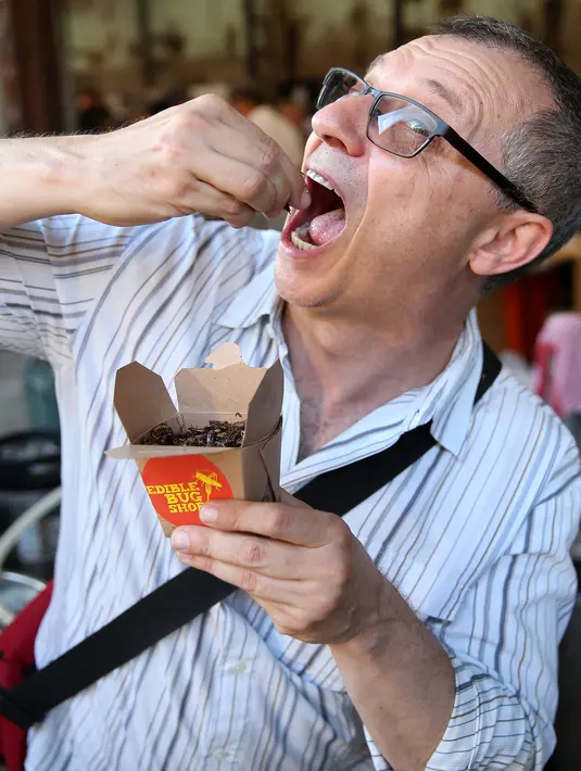 Seorang pria mencoba makanan berbahan dasar serangga yang dibelinya dari sebuah kios di Sydney, Australia, Sabtu (28/4). Kecoa panggang, semut rasa madu, larva berlapis coklat dsb tersedia di kios tersebut. (AFP FOTO / ANDREW MURRAY )