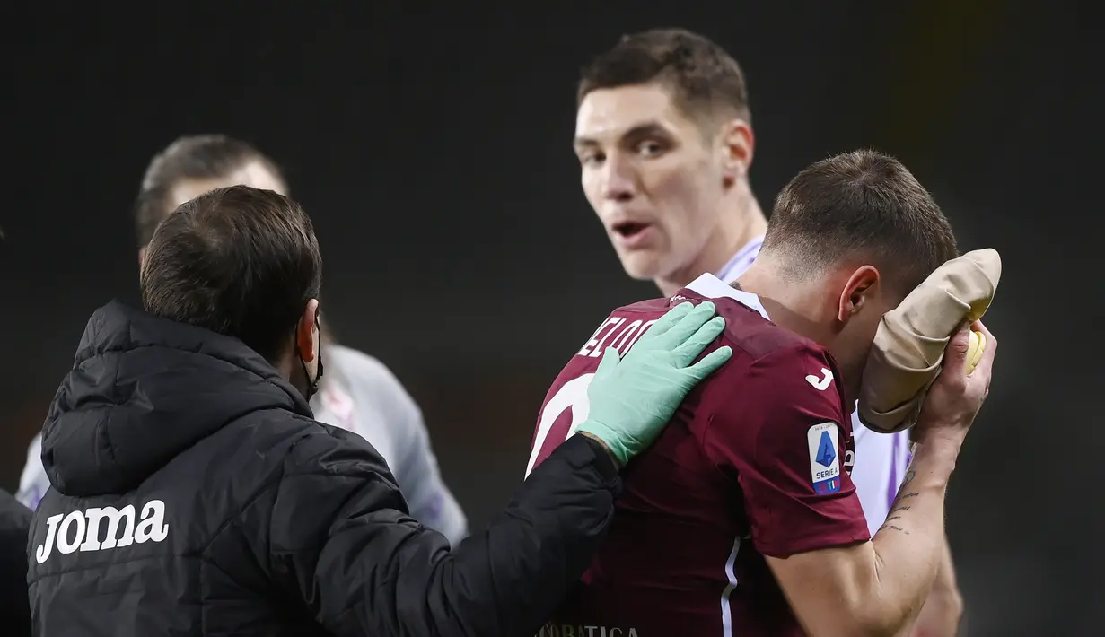 Striker Torino, Andrea Belotti (kanan) mendapat perawatan usai ditanduk bek Fiorentina, Nikola Milenkovic dalam laga lanjutan Liga Italia 2020/21 pekan ke-20 melawan Fiorentina di Olympico Grande Stadium, Jumat (29/1/2021). Torino bermain imbang 1-1 dengan Fiorentina. (LaPresse via AP/Fabio Ferrari)