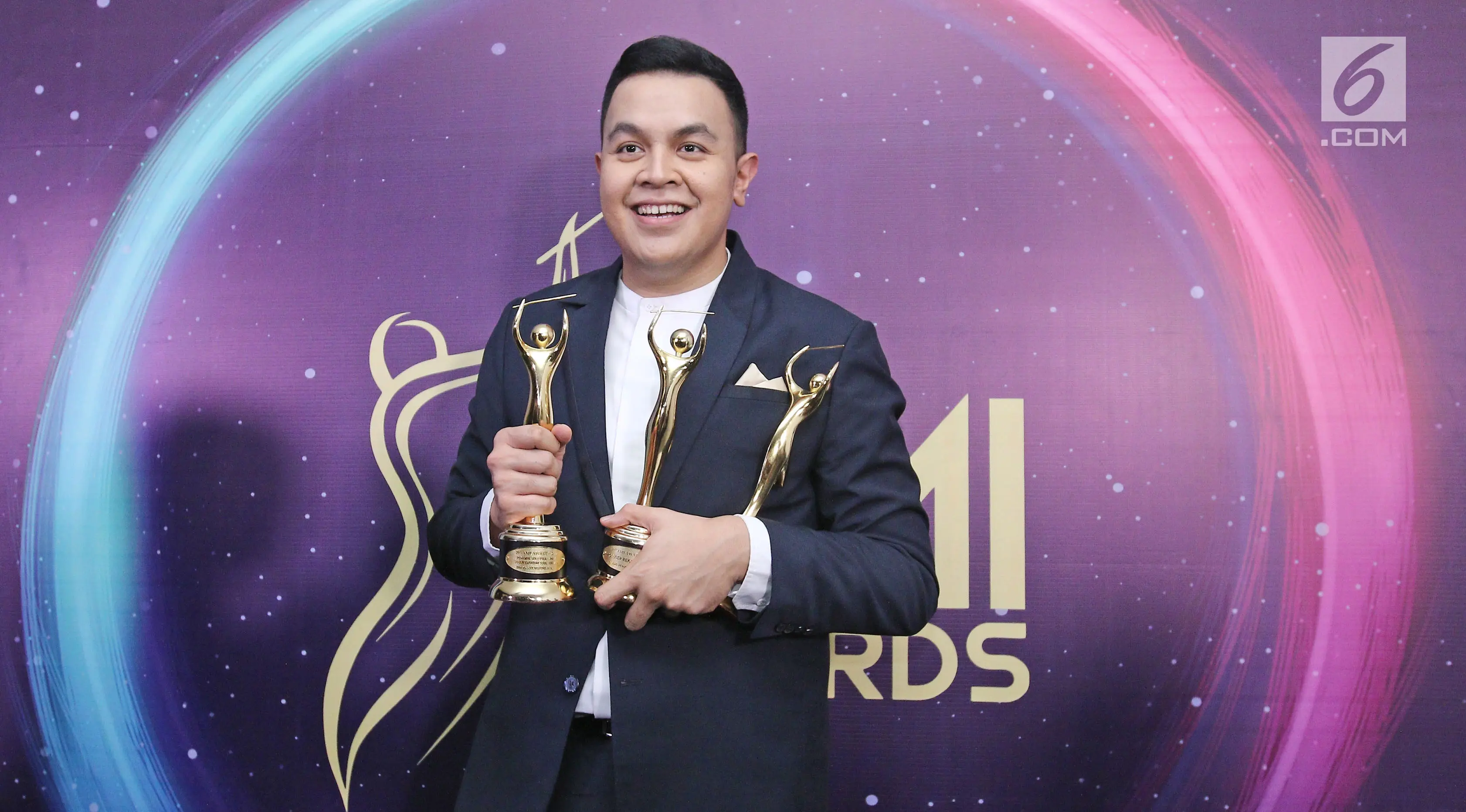 Penyanyi Tulus berpose memenggang piala usai meraih penghargaan Anugerah Musik Indonesia (AMI) Awards 2017 di Teater Garuda TMII, Jakarta, Kamis (16/11). Tulus berhasil membawa pulang empat piala. (Liputan6.com/Herman Zakharia)