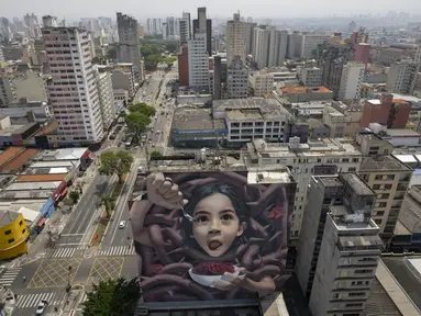 Sebuah mural raksasa karya seniman yang dikenal sebagai BIP, dipajang di dinding bangunan di Sao Paulo, Brasil, Rabu (29/9/2021). Para seniman mural papan atas dikerahkan membuat lukisan raksasa karya terbaik mereka untuk berpartisipasi dalam festival selama seminggu. (AP Photo/Andre Penner)