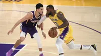 Bintang Lakers LeBron James (kanan) berduel dengan Devin Booker dari Phoenix Suns pada play-off NBA (AP)