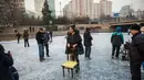 Seorang wanita menggunakan kursi untuk bermain ice skating atau seluncur es di atas sungai yang telah membeku di Beijing, Jumat (1/1). Semenjak membeku, sungai di Beijing ini menjadi objek wisata dadakan yang banyak diminati wisatawan.  (AFP/Fred Dufour)