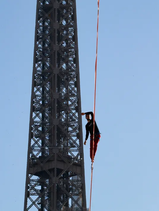 Nathan Paulin menyeimbangkan kaki di seutas tali saat menyeberang dari Menara Eiffel menuju alun-alun Trocadero, Paris, 9 Desember 2017. Aksi itu bagian dari Telethon ke-31 untuk menggalang dana kegiatan penelitian penyakit langka. (JACQUES DEMARTHON/AFP)