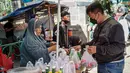 Penjual bunga tabur melayani pembeli di TPU Karet Tengsin, Jakarta, Minggu (27/3/2022). Sebagian warga memanfaatkan waktu jelang Ramadan menjadi penjual bunga tabur musiman untuk memenuhi kebutuhan ziarah ke makam yang dijual Rp 5.000 - Rp 20.000 per kantong plastik. (Liputan6.com/Faizal Fanani)