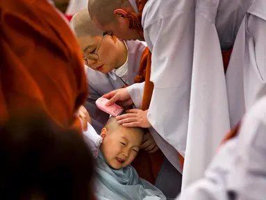 Seorang anak dicukur kepalanya oleh seorang Biksu saat upacara pemberkatan Biksu di kuil Jogye, Seoul, Senin (11/5/2015). Upacara ini diadakan bertepatan dengan hari ulang tahun Buddha. (REUTERS/Thomas Peter)