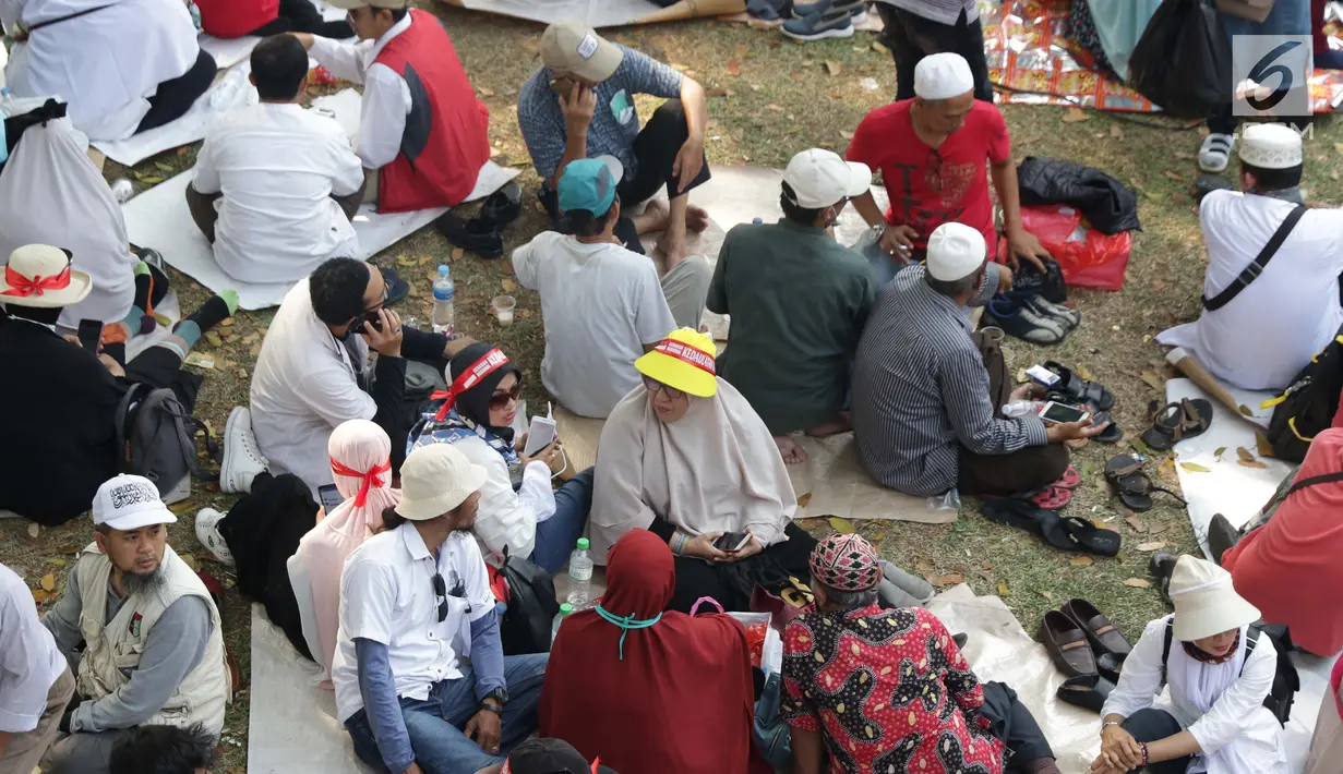 Massa aksi duduk-duduk beristirahat di taman pembatas Jalan Medan Merdeka Barat, Jakarta, Kamis (27/6/2019). Massa aksi berkumpul terkait pelaksanaan sidang putusan perselisihan hasil Pilpres 2019 di Gedung Mahkamah Konstitusi. (Liputan6.com/Helmi Fithriansyah)