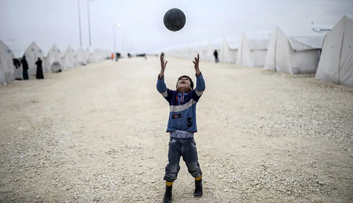 Bocah Syria bermain sepak bola di kamp pengungsian di Suruc, Propinsi Sanliurfa. (AFP PHOTO / BULENT KILIC)