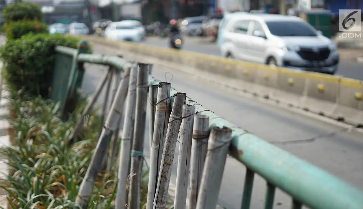 Kondisi pagar pembatas jalur transjakarta yang ditopang bambu di Jalan Otista Raya, Jakarta, Jumat (5/7/2019). Meskipun telah lama rusak, pagar besi berjeruji yang berfungsi sebagai pembatas agar orang tidak menyeberang secara sembarangan itu belum juga diperbaiki. (Liputan6.com/Immanuel Antonius)