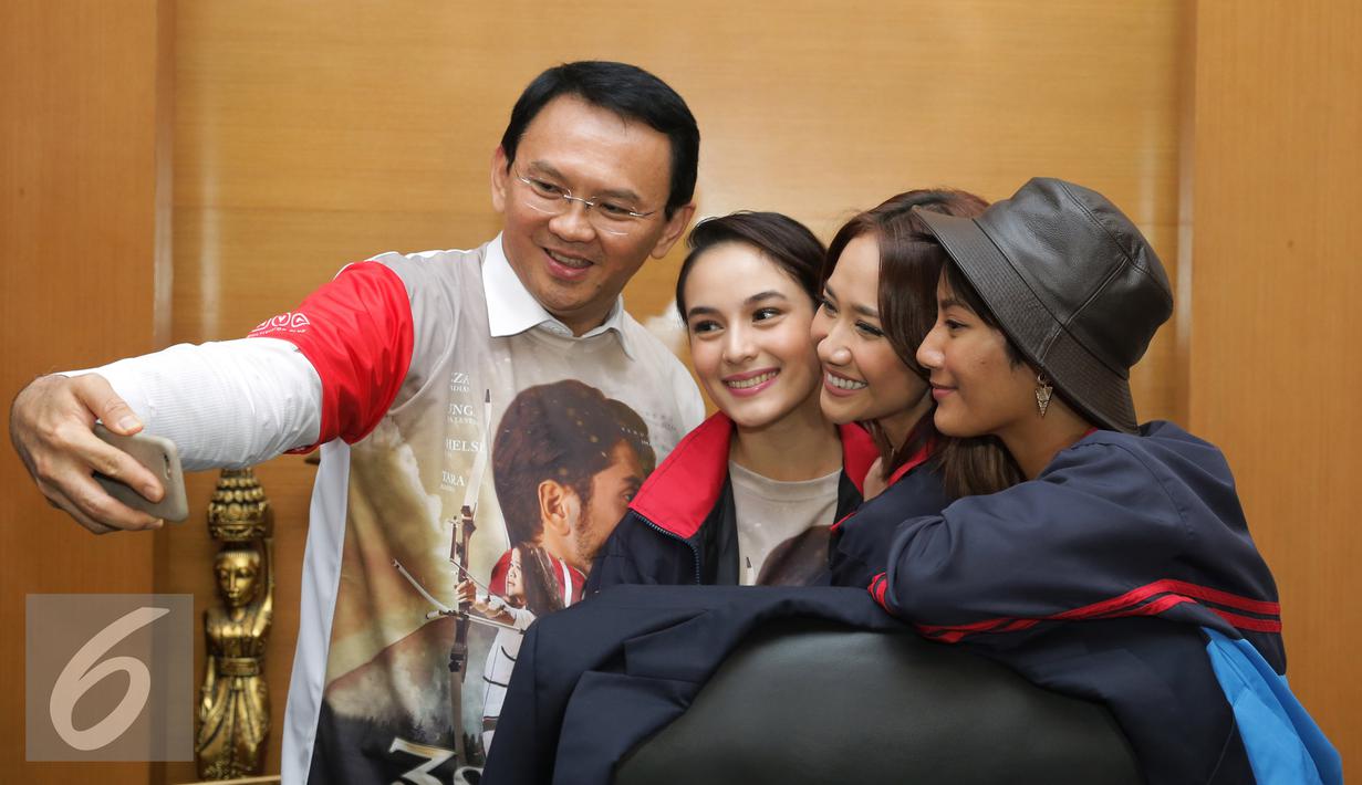 Gubernur DKI Jakarta Basuki Tjahaja Purnama selfie dengan pemain film 3 Srikandi di Balai Kota, Jakarta, Selasa (19/7). Film 3 Srikandi melakukan promo ke kantor Gubernur DKI Jakarta untuk menonton bareng bersama. (Liputan6.com/Herman Zakharia)