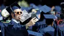 Peserta wisuda berswafoto dengan latar belakang penampilan Jon Bon Jovi pada pesta kelulusan Universitas Fairleigh Dickinson di New Jersey, Selasa (16/5). Jon Bon Jovi memberikan kejutan kepada peserta wisuda di universitas itu. (AP Photo/Julio Cortez)